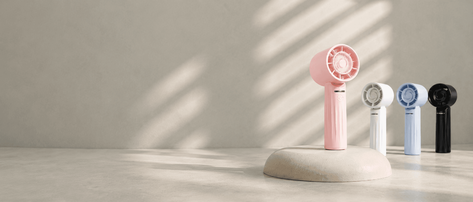 Pink handheld fan on a stone pedestal with white, blue, and black fans behind.